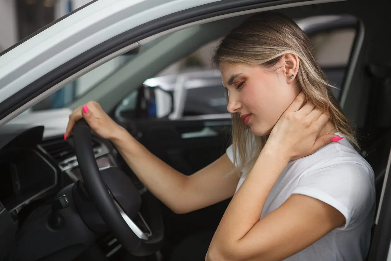 Young woman suffering from neck whiplash, sitting in driver's seat of her car. If you've been injured in a car accident, our Houston car accident attorneys are ready to fight for you. 