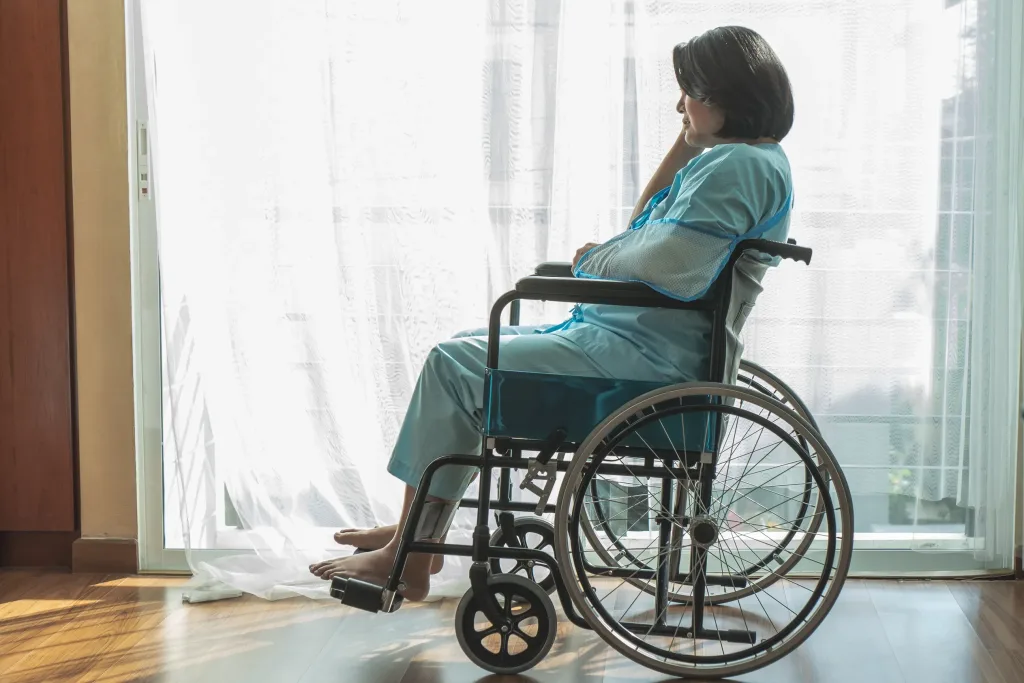 Woman sitting in a wheelchair next to a window.