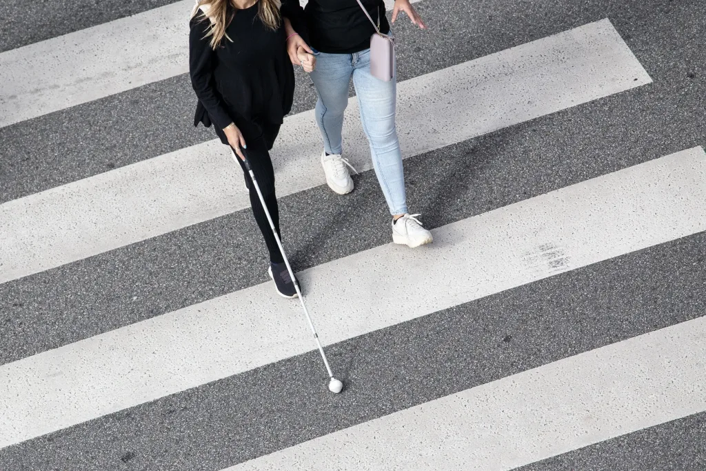 Blind woman and companion walking in a crosswalk.